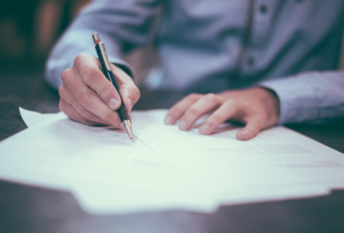 A man's hand signing a piece of paper